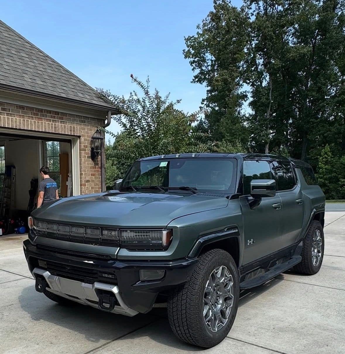 A matte green GMC Hummer EV with a dusty finish before an exterior detail.
